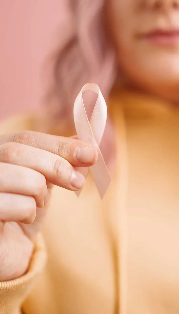 A woman holding a pink awareness ribbon